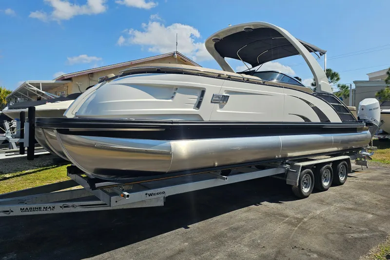 The Image of 2025 Bennington QX 27 QXSBWA X2 Swingback pontoon boat on trailer, sunny day. - 0