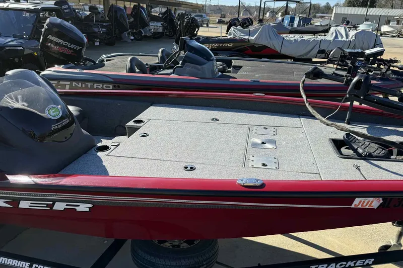 Slide: The Image of 2021 Tracker Pro Team 190 TX boat, red exterior, parked in a marina. - 2