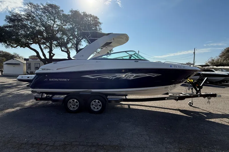 Slide: The Image of 2011 Monterey 264 FS boat on trailer, parked outdoors under clear sky. - 3