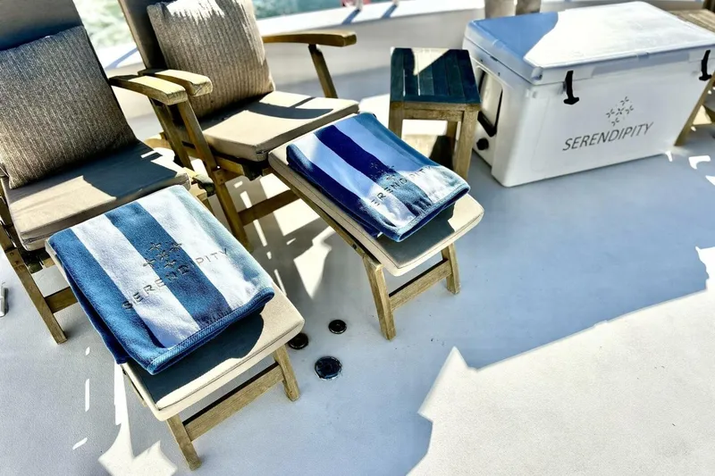 Slide: The Image of Deck of 2001 Lazzara 94 Motor Yacht with chairs, towels, and cooler labeled "Serendipity." - 54