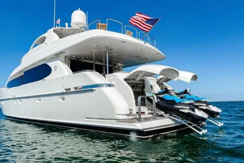 Slide: The Image of 2001 Lazzara 94 Motor Yacht with jet skis, American flag, on clear blue water. - 80