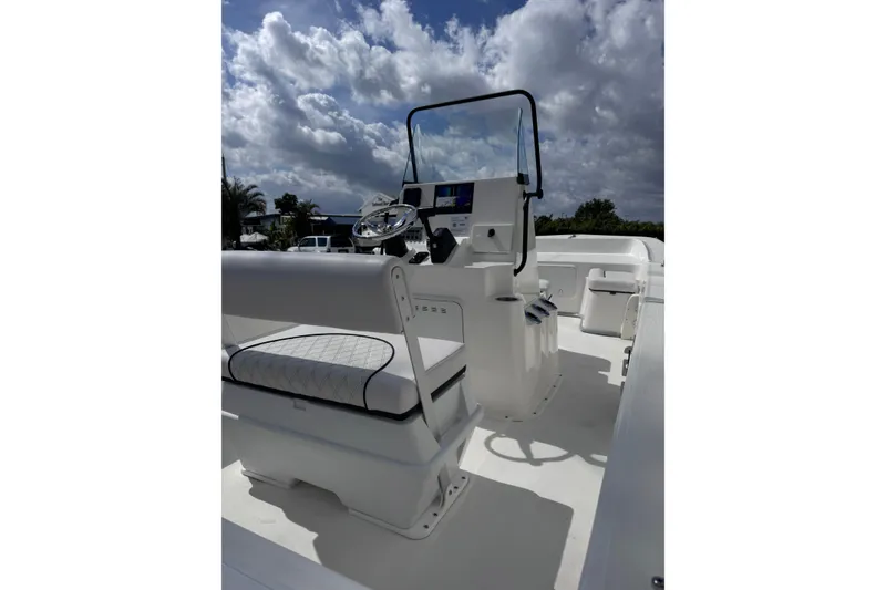 Slide: The Image of 2026 Sundance B20CCR boat interior with steering console, white seating, and cloudy sky backdrop. - 6