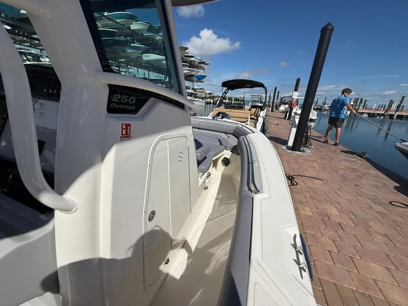 Slide: The Image of A 2027 Boston Whaler 250 Outrage is docked on a sunny day. A man stands nearby. - 13