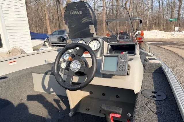 Slide: The Image of 2009 Lowe Fishing Machine 165 boat dashboard with steering wheel and navigation equipment. - 5
