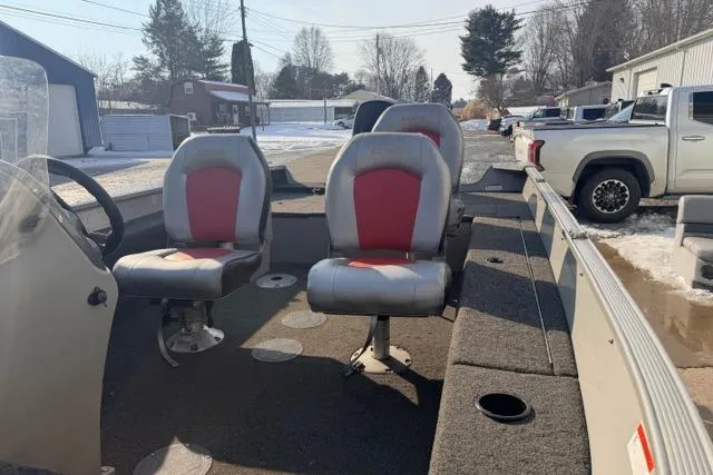 Slide: The Image of 2009 Lowe Fishing Machine 165 boat interior with red and gray seats, parked outdoors. - 7