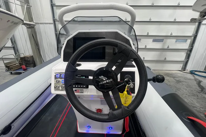 Slide: The Image of 2025 Highfield Velox 420 boat dashboard with steering wheel and control panel in a garage. - 12