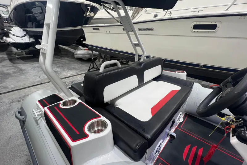 Slide: The Image of 2025 Highfield Velox 420 boat interior with black and white seating, cup holders, and steering wheel. - 9