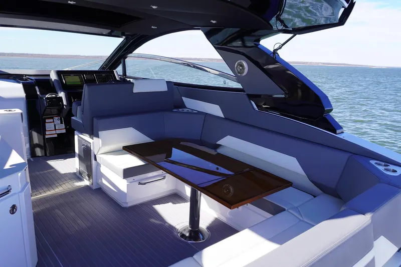 Slide: The Image of 2023 Cruisers Yachts 42 GLS OB interior with sleek seating and table, overlooking the ocean. - 11