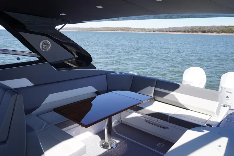 Slide: The Image of 2023 Cruisers Yachts 42 GLS OB interior with sleek seating and table, overlooking serene waters. - 12