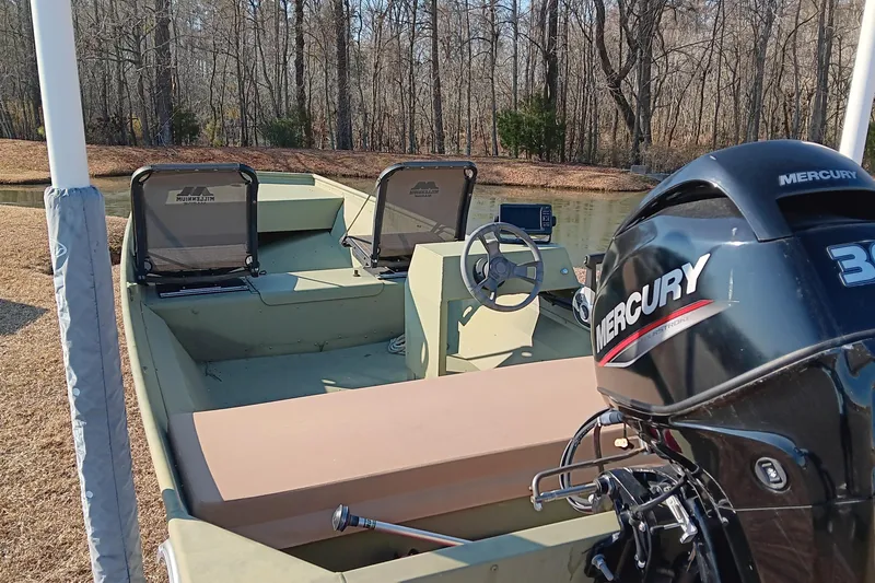 Slide: The Image of 2022 Lowe L1648M Jon boat with Mercury engine, parked by a wooded lake. - 11