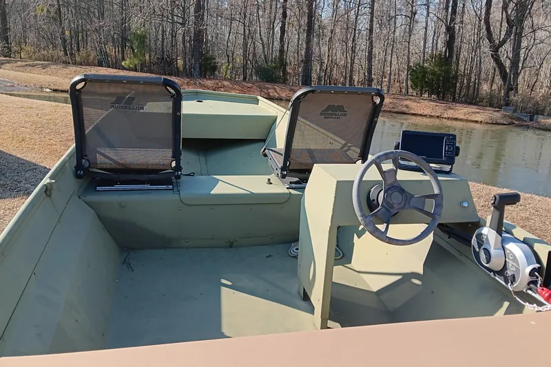 Slide: The Image of 2022 Lowe L1648M Jon boat interior with steering wheel and seats by a pond. - 12