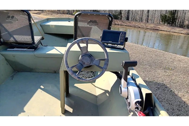 Slide: The Image of 2022 Lowe L1648M Jon boat interior with steering wheel and control panel by a pond. - 13