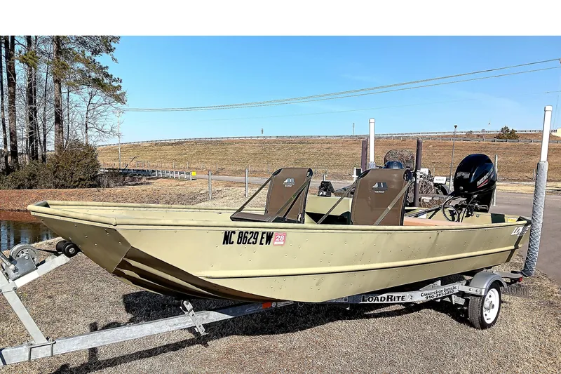 Slide: The Image of 2022 Lowe L1648M Jon boat on trailer, parked outdoors near a lake. - 3