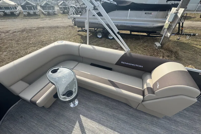 Slide: The Image of 2026 Bennington 20 SL pontoon boat interior with beige seating and cupholder table. - 12