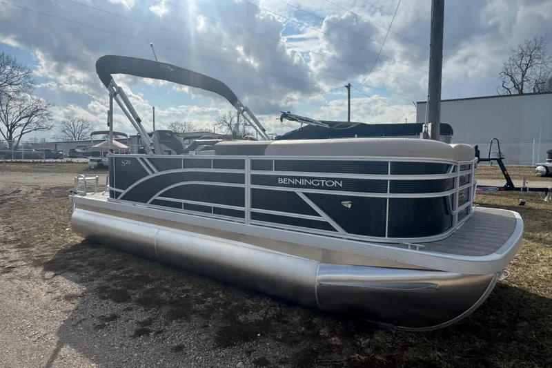 Slide: The Image of 2026 Bennington 20 SL pontoon boat parked outdoors under a cloudy sky. - 2