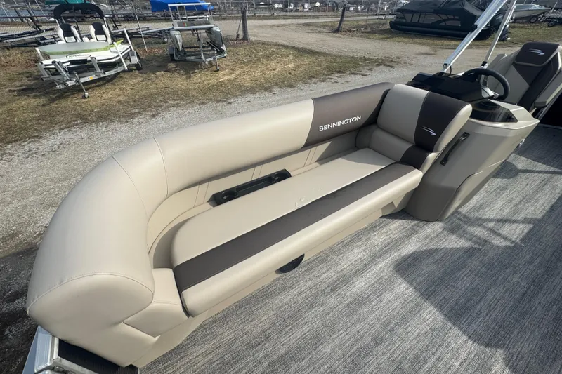 Slide: The Image of 2026 Bennington 20 SL boat with beige and brown seating, parked outdoors. - 5