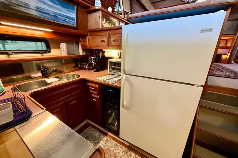 Slide: The Image of 1987 Carver 4207 Aft Cabin Motor Yacht kitchen with fridge, sink, and wooden cabinetry. - 34