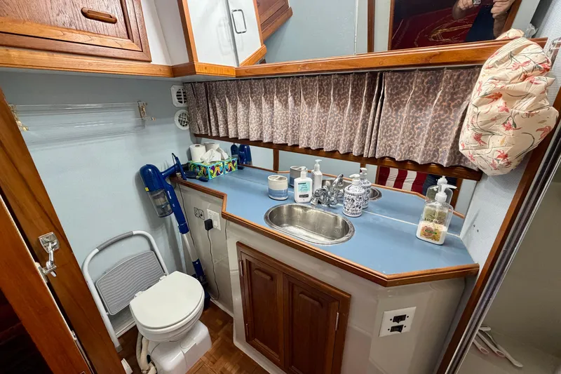 Slide: The Image of 1987 Carver 4207 Aft Cabin Motor Yacht bathroom with sink, toilet, and storage cabinets. - 46