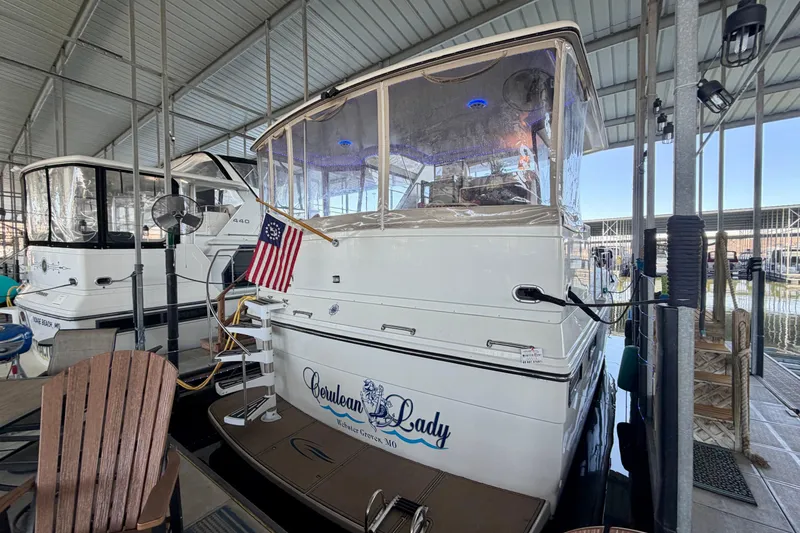 Slide: The Image of 1987 Carver 4207 Aft Cabin Motor Yacht docked, featuring an American flag and covered seating area. - 2