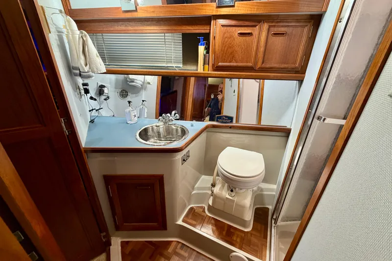 Slide: The Image of 1987 Carver 4207 Aft Cabin Motor Yacht bathroom with sink, toilet, and wooden cabinetry. - 40