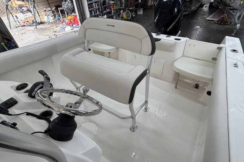 Slide: The Image of 2022 Sailfish 242 CC boat interior with steering wheel and seating in a workshop. - 17