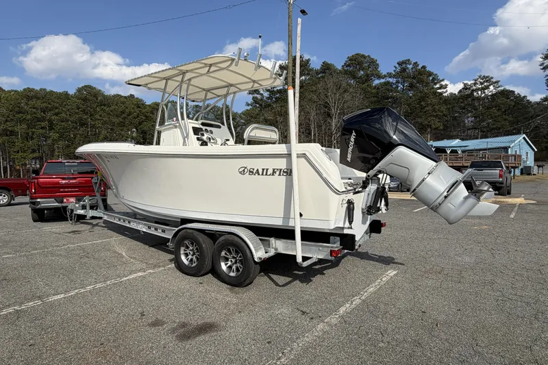 Slide: The Image of 2022 Sailfish 242 CC boat on trailer, parked in a lot with trees and vehicles. - 3