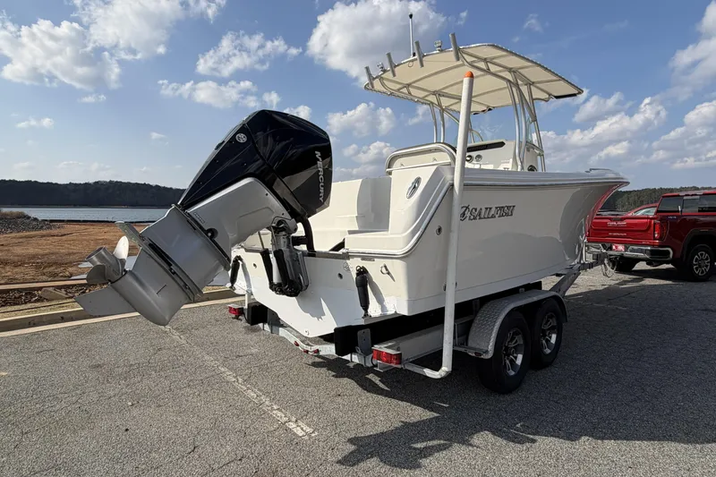 Slide: The Image of 2022 Sailfish 242 CC boat on trailer with outboard motor, parked near a lake. - 4