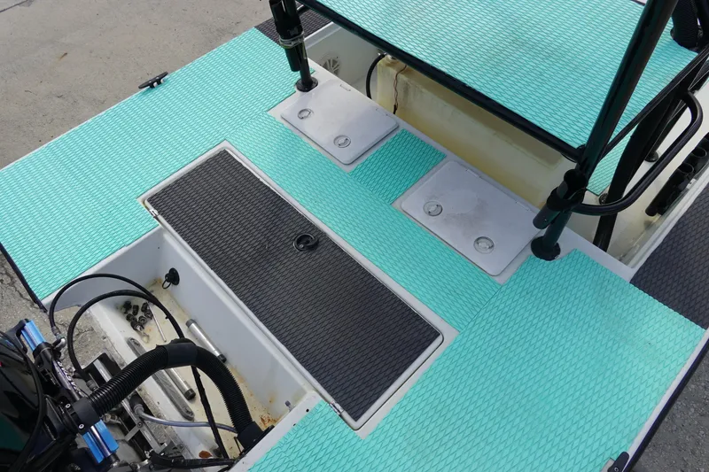 Slide: The Image of 1999 Stott Craft 1900 boat deck with teal non-slip flooring and storage compartments. - 11