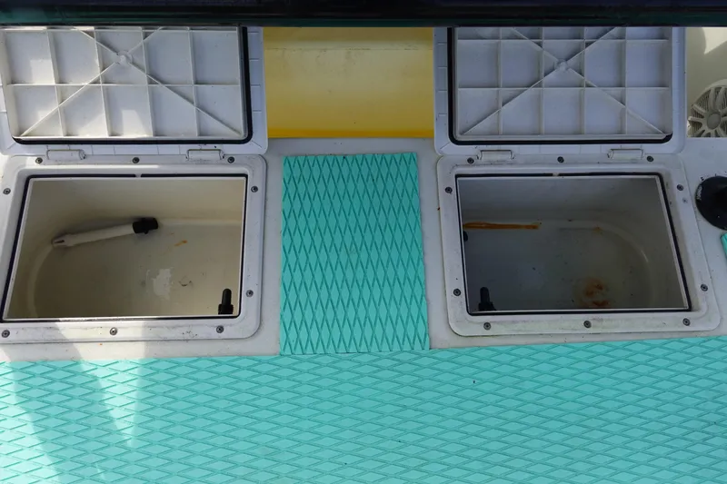 Slide: The Image of Open storage compartments on a 1999 Stott Craft 1900 boat with turquoise flooring. - 13
