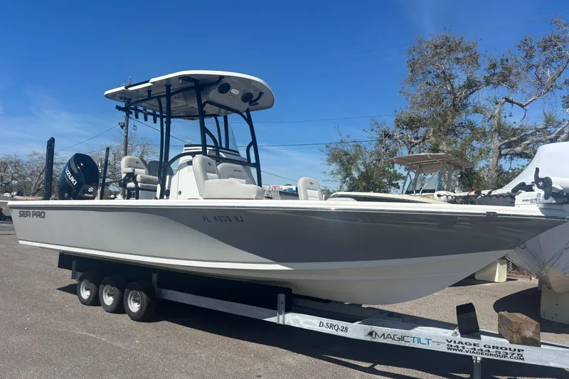 Slide: The Image of 2019 Sea Pro 248 Bay boat on trailer, parked outdoors under clear blue sky. - 0
