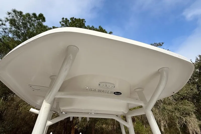Slide: The Image of 2024 Tidewater 2300 Carolina Bay boat T-top against a blue sky and trees. - 22