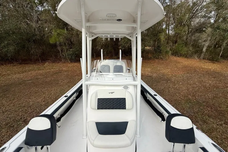 Slide: The Image of 2024 Tidewater 2300 Carolina Bay boat with T-top, white seating, and wooded background. - 23