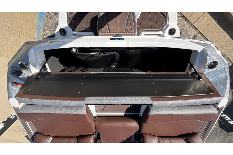 Slide: The Image of 2026 Tigé Ultré 25ZX boat interior with open storage compartment and brown seating. - 16