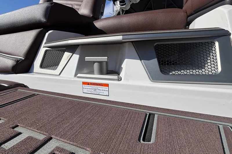 Slide: The Image of 2026 Tigé Ultré 25ZX boat interior with brown seating and warning label. - 18