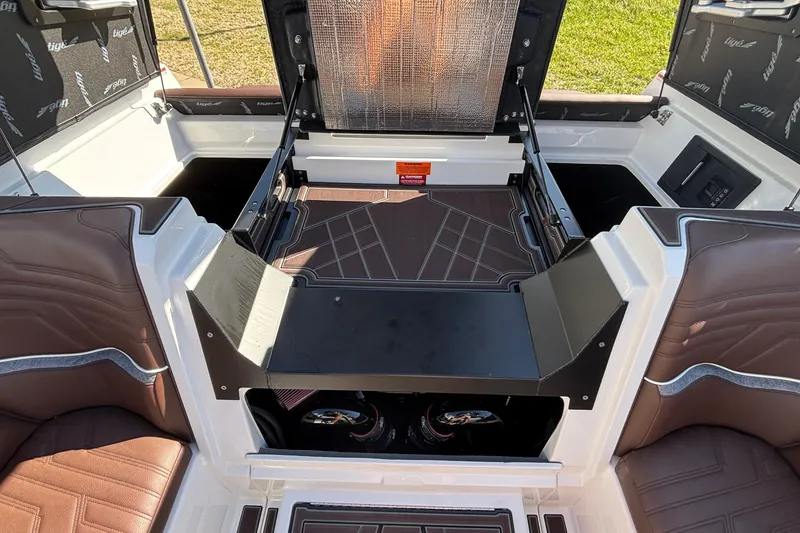 Slide: The Image of 2026 Tigé Ultré 25ZX boat interior with brown seating and storage compartments. - 26