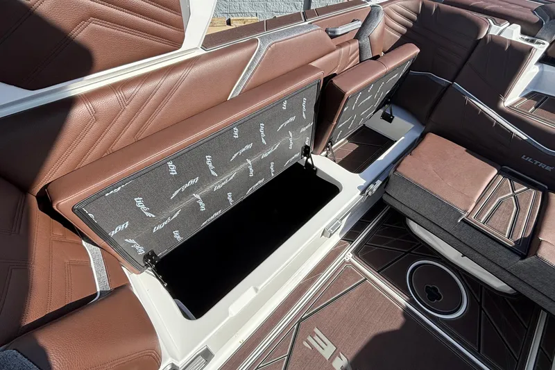 Slide: The Image of 2026 Tigé Ultré 25ZX boat interior with open storage compartment and brown seating. - 80