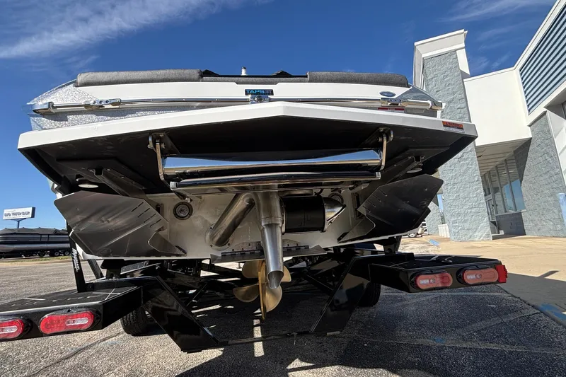 Slide: The Image of 2026 Tigé Ultré 25ZX boat rear view, showcasing propeller and trailer in a sunny setting. - 83