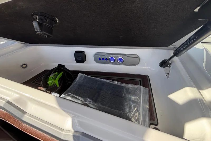 Slide: The Image of Storage compartment of 2026 Tigé Ultré 25ZX boat with battery switches and accessories. - 85