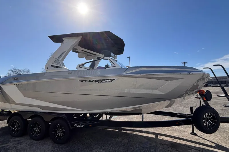 Slide: The Image of 2026 Tigé Ultré 25ZX boat on trailer under bright sunlit sky. - 90