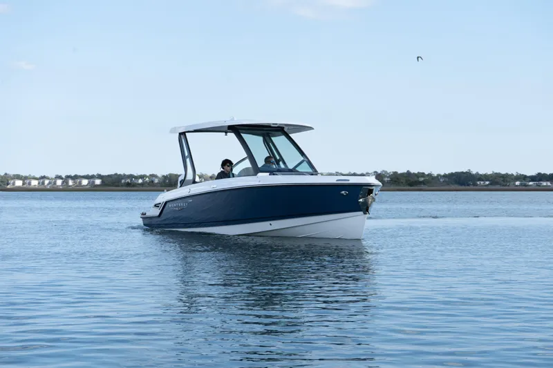 Slide: The Image of 2026 Monterey Elite 27 OB boat cruising on calm waters under a clear sky. - 11