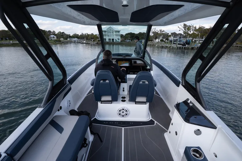 Slide: The Image of 2026 Monterey Elite 27 OB boat interior with modern seating and dashboard on a calm waterway. - 14