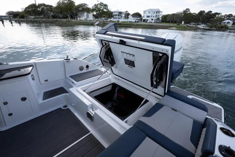 Slide: The Image of 2026 Monterey Elite 27 OB boat with open storage compartment on a serene lake. - 21