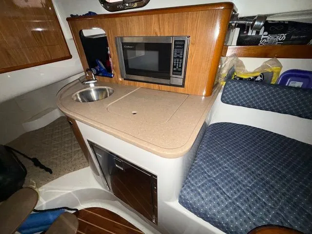 Slide: The Image of 2008 Pursuit OS 285 Offshore kitchen area with microwave and sink. - 11