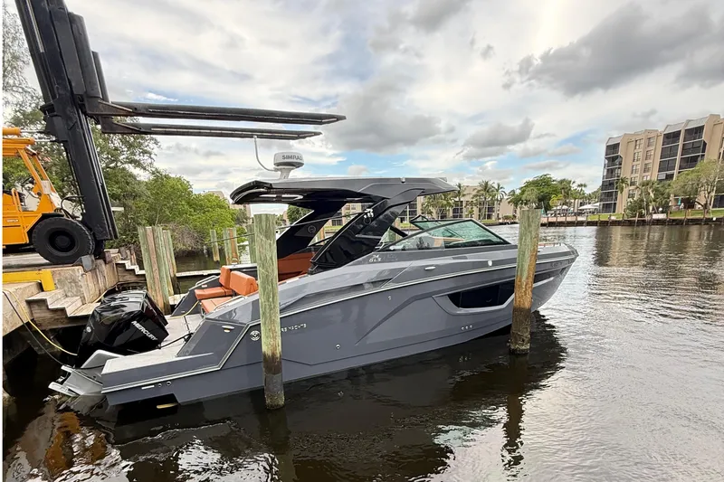 Slide: The Image of 2023 Cruisers Yachts 34 GLS OB docked on a calm river with modern buildings. - 3