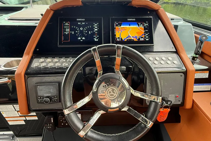 Slide: The Image of 2023 Cruisers Yachts 34 GLS OB helm with dual Simrad displays and leather-wrapped steering wheel. - 5
