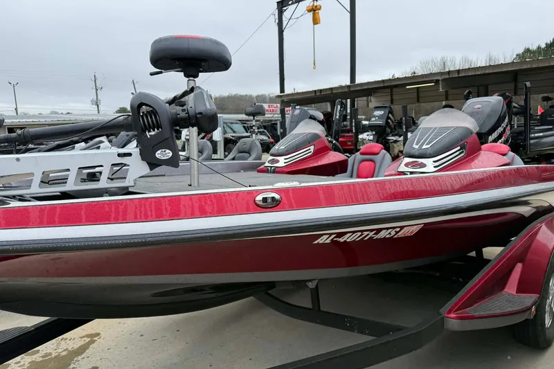 Slide: The Image of 2015 Ranger Z518 Comanche boat in red, parked on a trailer at a marina. - 2