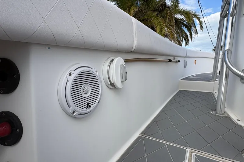 Slide: The Image of 2006 Bluewater 2850 CC boat deck with speaker, cushioned railing, and palm trees in background. - 12