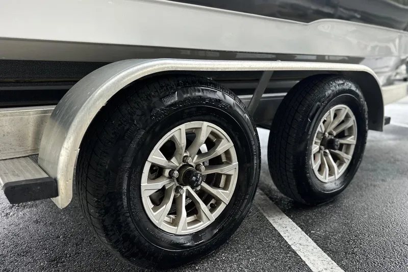 Slide: The Image of Trailer wheels of a 2026 Sea Hunt Ultra 245 SE boat on wet pavement. - 29