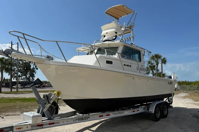 Slide: The Image of 2019 Parker 2520 XLD Sport Cabin boat on trailer, sunny day, palm trees in background. - 3