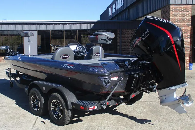 Slide: The Image of 2025 Triton 19 TrX Patriot boat with powerful engine, parked outside a building. - 3